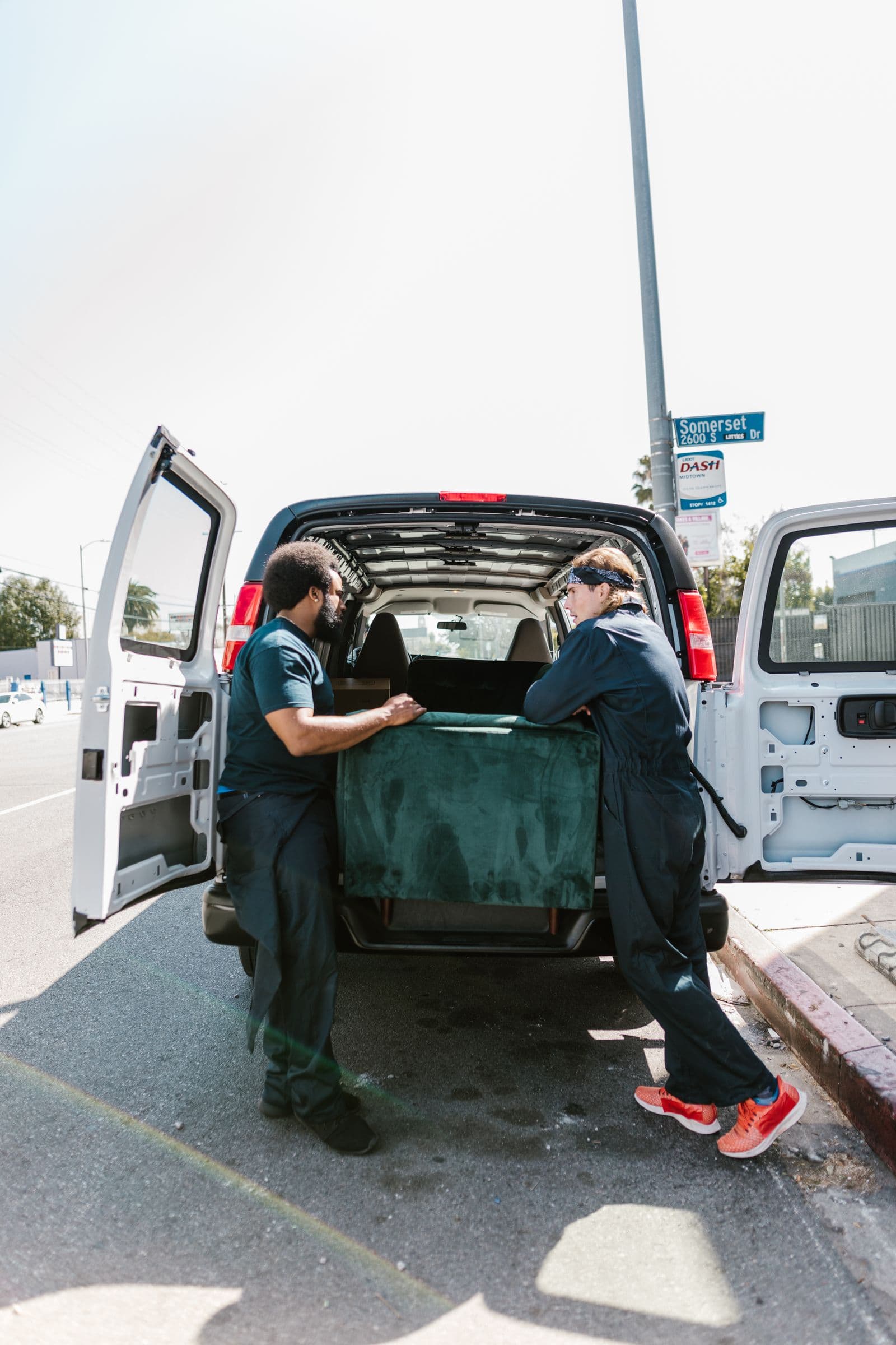 Two-person crew loading a sofa into a haul-away van on a Central Texas street